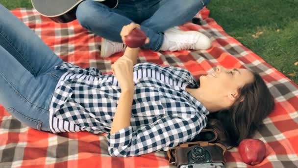 约会的情侣 在格子上躺着的年轻女子 有乐趣和 Listetning 他的男朋友弹吉他 — 图库视频影像
