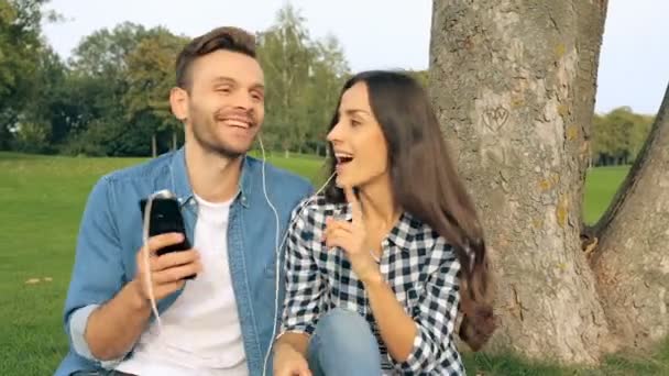 快乐的年轻夫妇一起听音乐在耳机 户外公园 — 图库视频影像