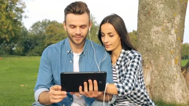 Young Couple Outdoors Sitting Tree Plaid Choosing Playlist Music Digital — Stock Video