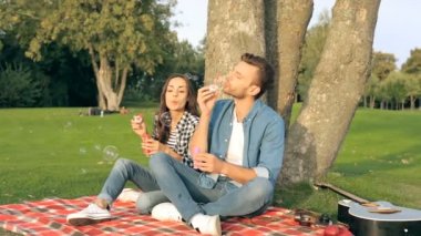 Ekose üzerinde oturan çift ağaç Park yakınındaki. Kabarcık üfleyiciler ile eğleniyor. 