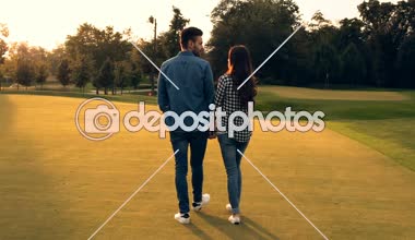 Elele ve açık havada yürüyen bir çift. Günbatımı zamanı. Arkadan görüntülemek.