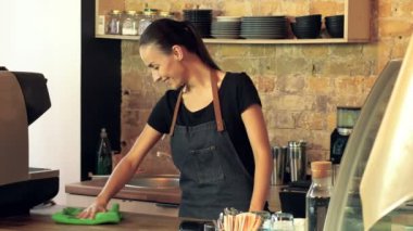 Kadın barista prepearing İşyeri ve Temizleme işlemi toz gülümseyerek. Steadycam atış.