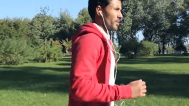 Parkta koşan yetişkin adam. Kulaklık müzik dinlemek.