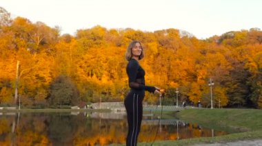 Genç kadın parkta duran yerleştirmek. Atlama ipi tutan, gülüyor ve kameraman ile konuşmak.