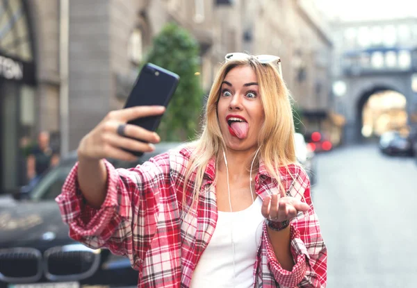 Dalga ve Smartphone'da selfies alarak tonque, gösterilen komik sarışın kadın.