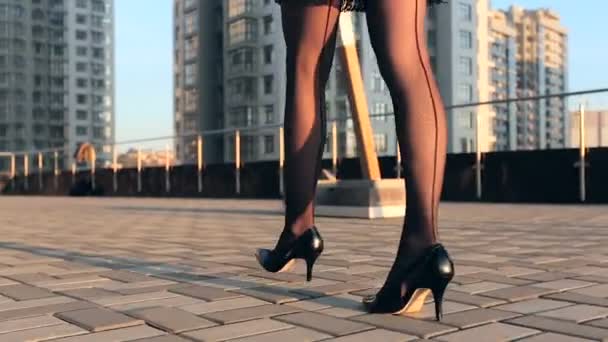 Woman legs in tights and black heels walking at the street.