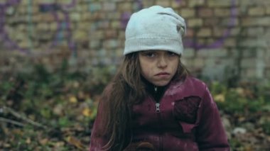 Harabeleri oturan ve kameraya bakarak evsiz kız.