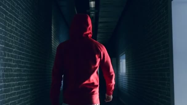 穿着红色卡普奇的家伙走在黑暗的走廊里 — 图库视频影像