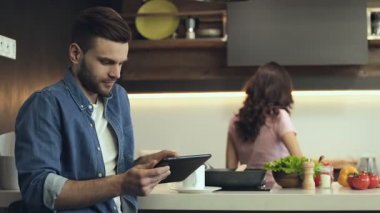 Çift mutfak at. Gülümseyen adam kadın yemek sırasında dijital tablet kullanma.