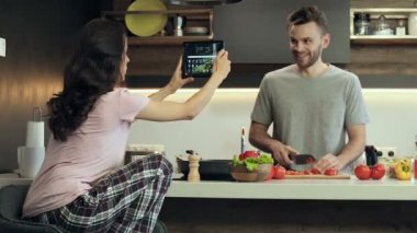İki yemek. Hazırlama salata adam ve sebze kesme. Onun karısı (ya da kız arkadaşı) eğleniyor ve dijital tablet üzerinde çekim video.