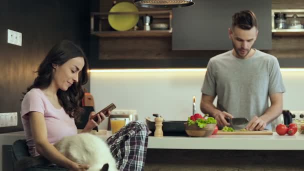 Casal Jovem Cozinha Mulher Segurando Smartphone Mensagens Homem Preparando Salada — Vídeo de Stock