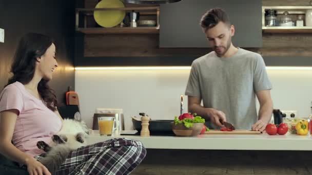 台所でのカップル ジュースを飲んで 猫を抱いての女性 キッチンでサラダを準備する彼氏 — ストック動画