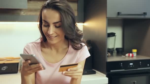 スマート フォンとクレジット カードを保持している魅力的な女性 オンライン決済を行う — ストック動画