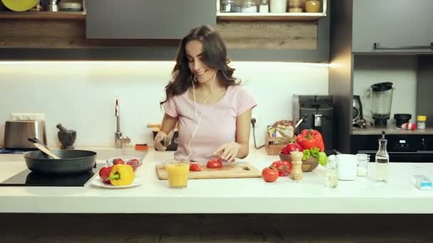 年轻的女人做饭 独自在厨房听音乐 — 图库视频影像