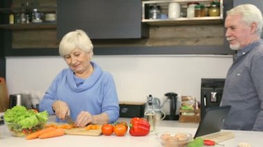 Yaşlı çift. Adam şaka ve barış havuç salatası hazırlama karısı süre alarak.