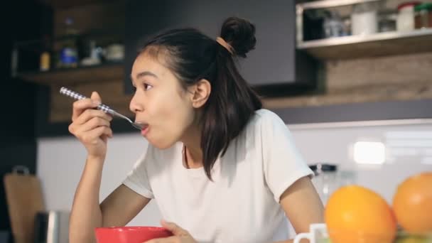 キッチンでコーンフレークを食べる若い女性の肖像画 — ストック動画
