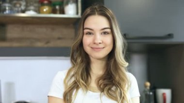 Arayan şirin, gülümseyen kadın portresi kamera ve Merhaba jest yapıyor. Mutfakta poz.