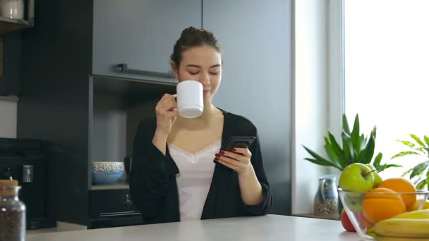 Ελκυστική Γυναίκα Πίνοντας Καφέ Πρωί Κρατώντας Smartphone Και Πληκτρολόγηση — Αρχείο Βίντεο