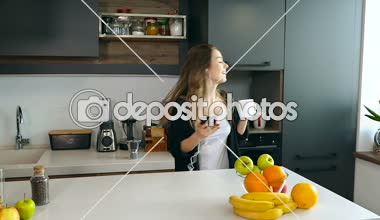 Mutlu kadın mutfakta eğleniyor. Smartphone holding, dans ve kahve içme.