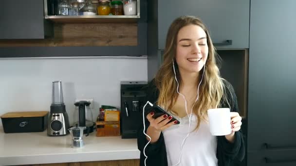 Hübsche Junge Frau Hört Musik Tanzt Trinkt Kaffee Der Küche — Stockvideo