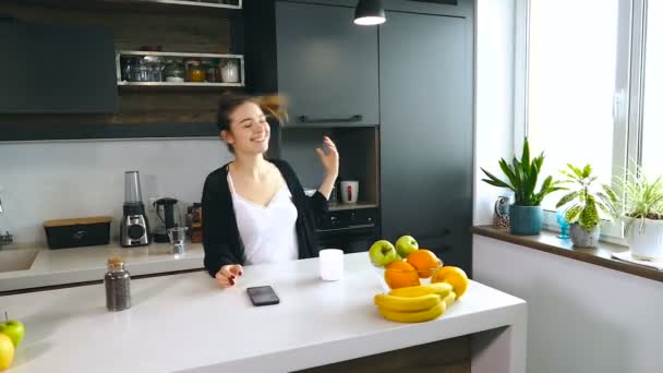 Mujer Sonriente Desatándose Pelo Beber Café Mirar Smartphone Casa Cocina — Vídeo de stock