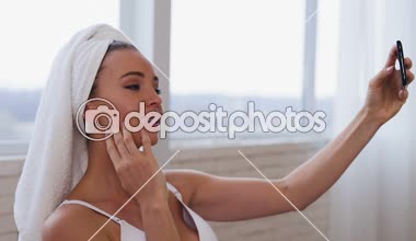 Evde duştan sonra kadın. Akıllı telefonda selfie 'ler alma.