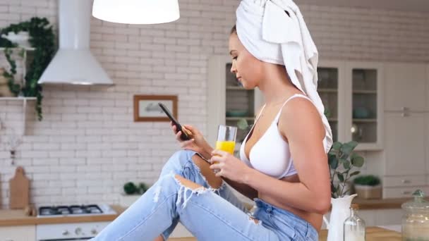 Young Woman Holding Glass Juice Sitting Kitchen Table Talking Smartphone — Stock Video