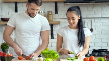 Genç çift salatası mutfak at hazırlanıyor. Gülüyor, gülüyor ve konuşmak.