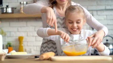 Kabın içinde yumurta karıştırma neşeli, tatlı küçük kız portresi. 