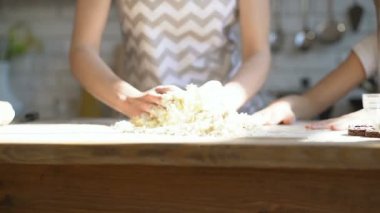 Kadın elleri mutfak masasında hamur yoğuruyor.