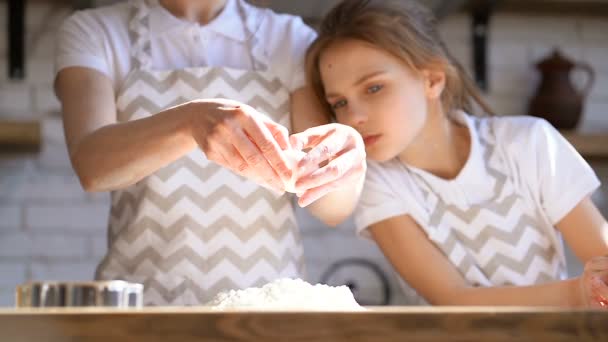 二人の姉妹 または母娘 が台所で生地を準備しています 小麦粉に卵を割る スローモーション — ストック動画