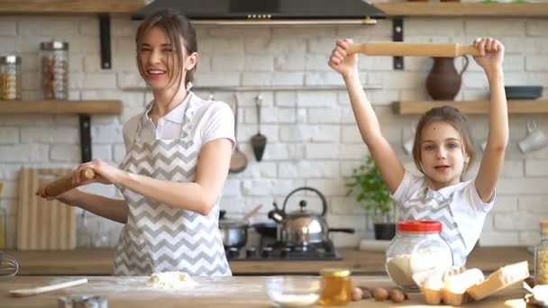 zwei Schwestern (oder Mutter-Tochter) haben Spaß, albern und tanzen mit Rollnadeln in der Küche.