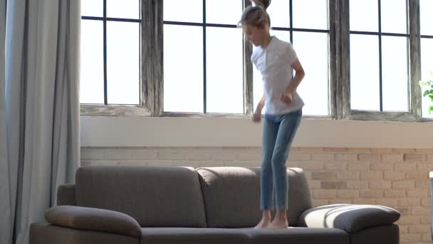 Niña Divirtiéndose Disfrutando Saltando Sofá — Vídeo de stock