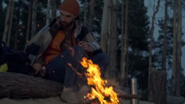 Kamp ateşinin yanında ekose giydiren bir adam. Akşam vakti. Slowmotion.