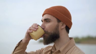 Gülümseyen sakallı adam güzel bir gün ve manzara zevk. Bardaktan çay (veya coffe) içmek.
