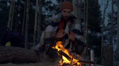 Kamp ateşinin yanında oturan ve elleri ısınan sakallı adam. Slowmotion.