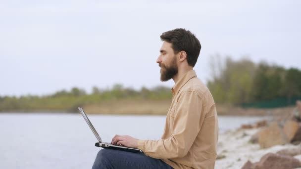 Knappe Baard Guy Freelancing Otdoors Zittend Aan Zeekust Werken Met — Stockvideo