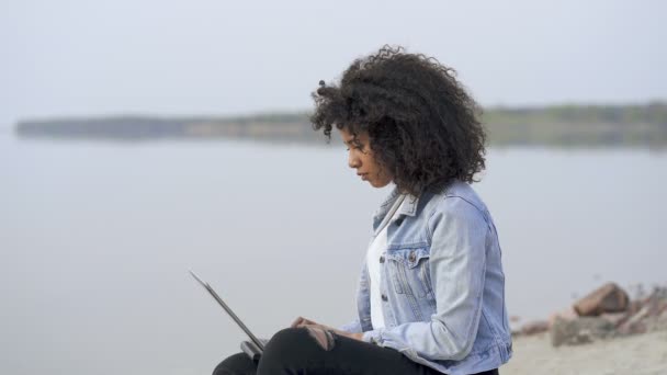 Νεαρή Αφρο Αμερικανίδα Που Δουλεύει Έξω Καθισμένος Κοντά Στη Θάλασσα — Αρχείο Βίντεο