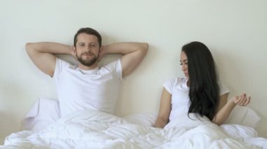 Yatakta yatan bir çift. Kız arkadaşı şaka ve büyüteç kullanarak potens kontrol. Erkek arkadaşı gülümsüyor ve kameraya bakıyor.