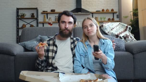 若いカップルリラックスして テレビを見て 家でピザを食べる — ストック動画