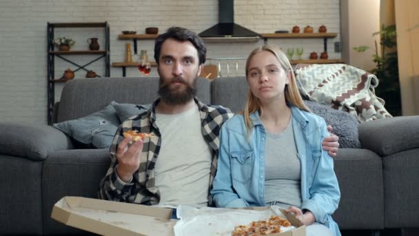 Pareja Comiendo Pizza Viendo Televisión Casa Mirando Cámara — Vídeo de stock