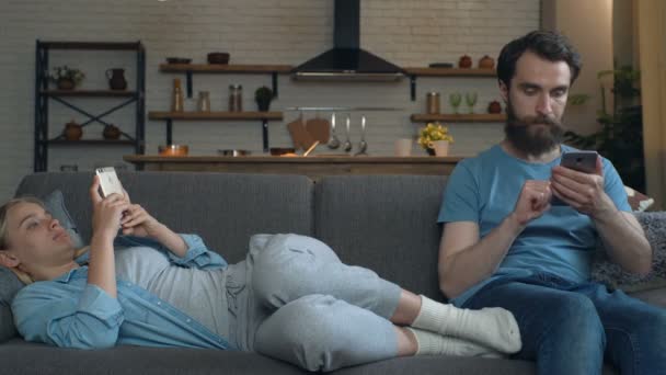 Young Couple Sitting Sofa Holding Smartphones Looking Them Talking Emotions — Stockvideo