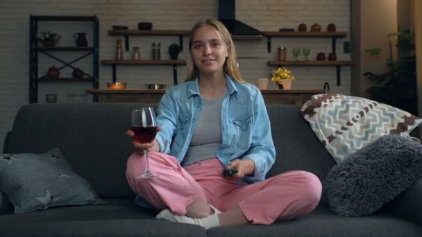 Mulher Loira Bonita Sentada Sofá Assistindo Noite Segurando Copo Vinho — Vídeo de Stock