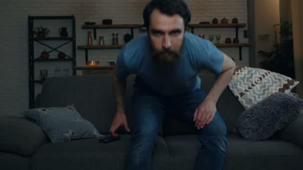 Junger Mann Sitzt Auf Dem Sofa Nimmt Fernbedienung Und Schaltet — Stockvideo