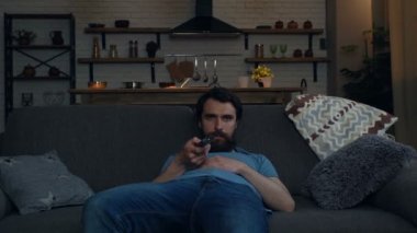 İşten sonra evde ki kanepede oturan yorgun adam. Uzaktan kumandalı televizyon tutmak ve kanal değiştirmek. Tv programı arıyorsunuz.