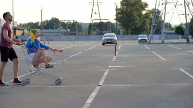 Arkadaşlar su tabancası kavgabaşlar. Park yerinin ortasında süpermarket arabalarıyla birbirlerine doğru yürüyorlar. Ciddi ve komik görünmeye çalışıyorum.