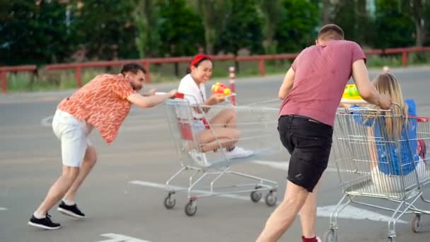 Grupo Cuatro Amigos Divirtiéndose Tiroteo Corriendo Aparcamiento Con Carros Supermercado — Vídeo de stock