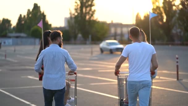 Otoparkta Yürüyen Dört Arkadaş Süpermarket Arabalarında Oturan Kızlar Konuşuyorlar Gülümsüyorlar — Stok video