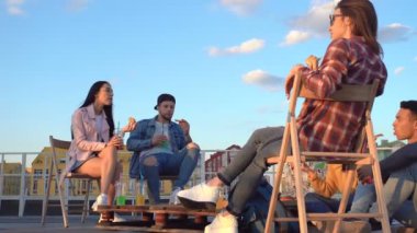 Bir grup arkadaş çatıda diniyor. Pizza yemek. Birbirimizle konuşuyoruz. El çekimi.