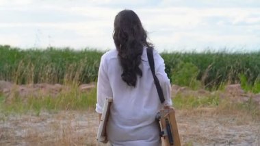 Genç Asyalı kadın çizim defteri yle dışarıda yürüyor. Arkadan bak. El çekimi.